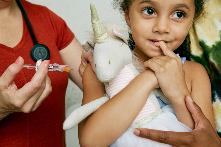Young girl about to receive a vaccine from a medical professional